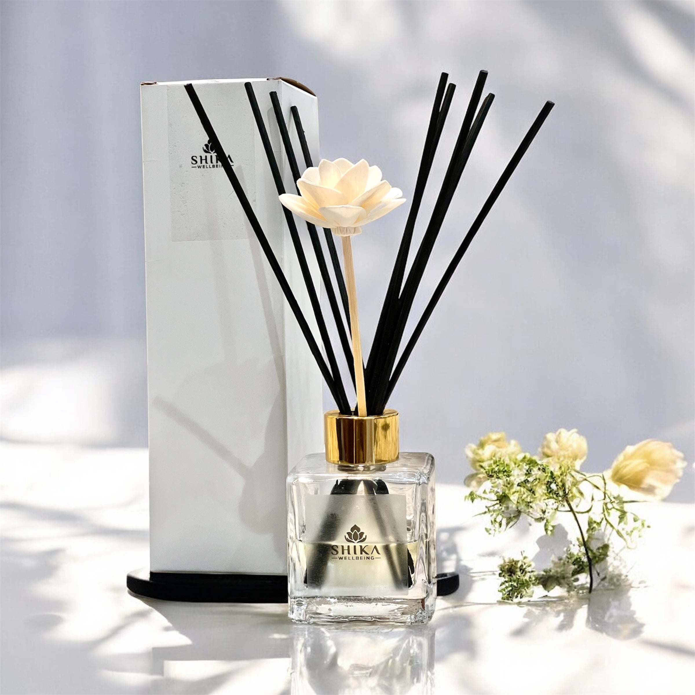Shika diffuser with black reeds and a white flower on a light background