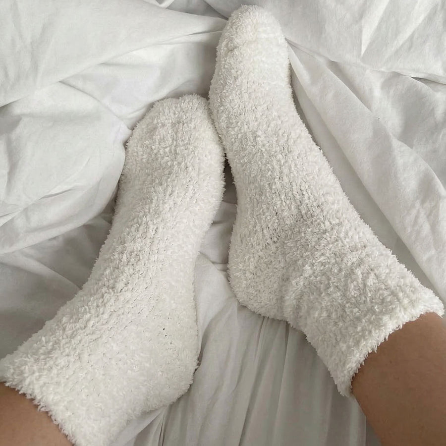 White fluffy socks on a white bed
