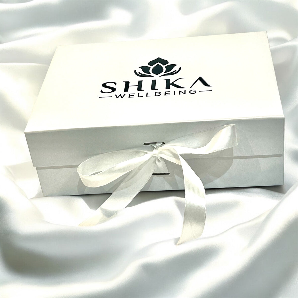 White gift box with a bow and Shika Wellbeing logo on a white fabric background