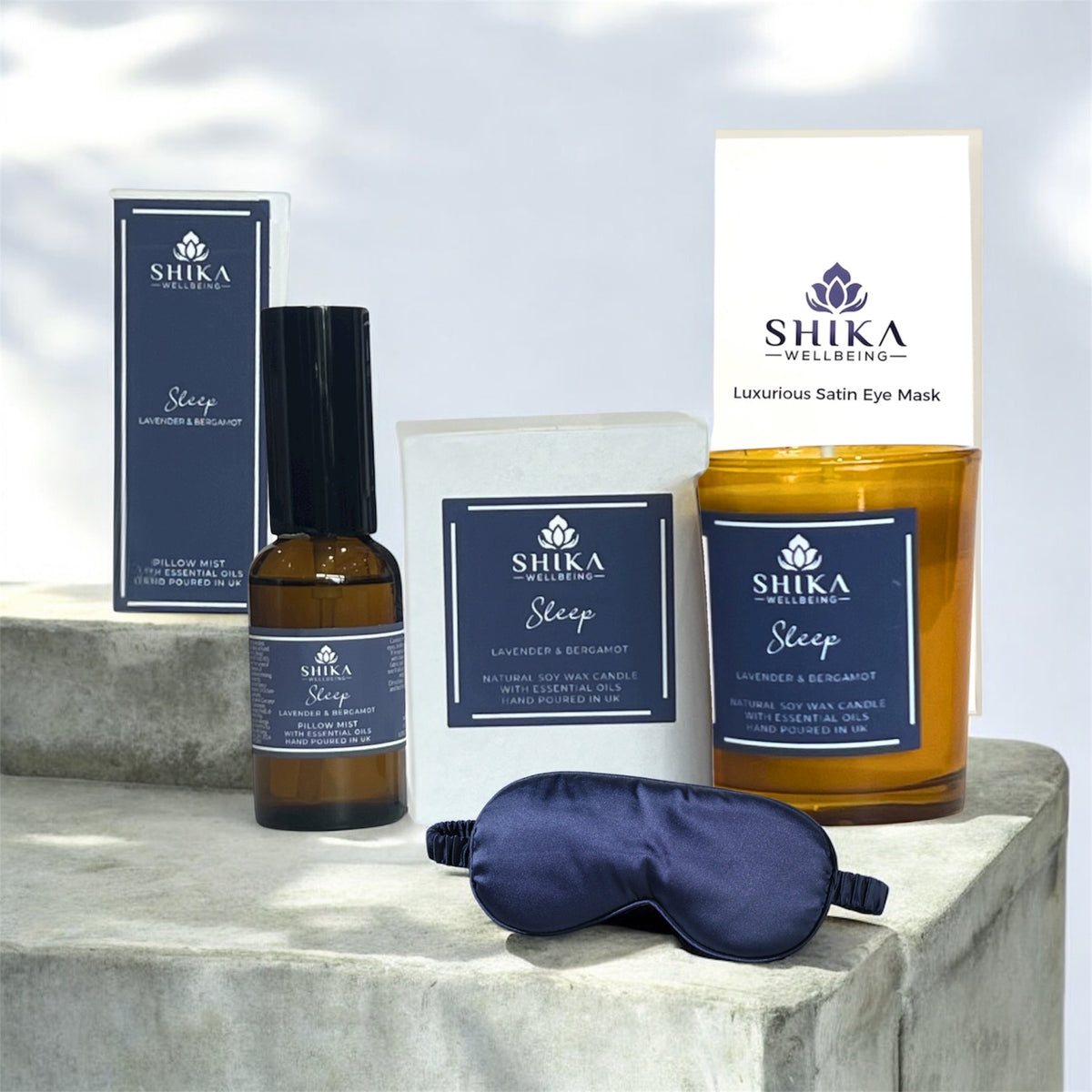 Shika Wellness sleep product set including a candle, eye mask, and bottle on a stone surface.