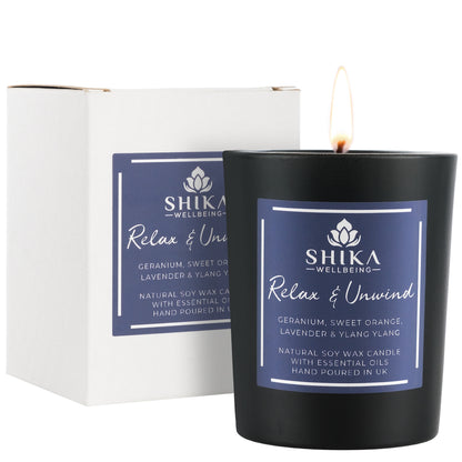Black candle with Shika Wellbeing label next to its packaging on a white background