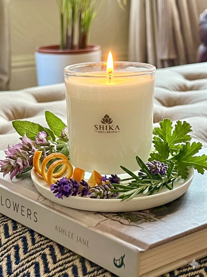 Shika Wellbeing candle on a book with flowers and leaves