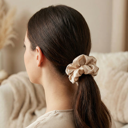 Woman with a beige scrunchie in her hair, sitting on a beige couch.