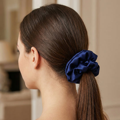 Woman with a blue scrunchie in her ponytail against a neutral background