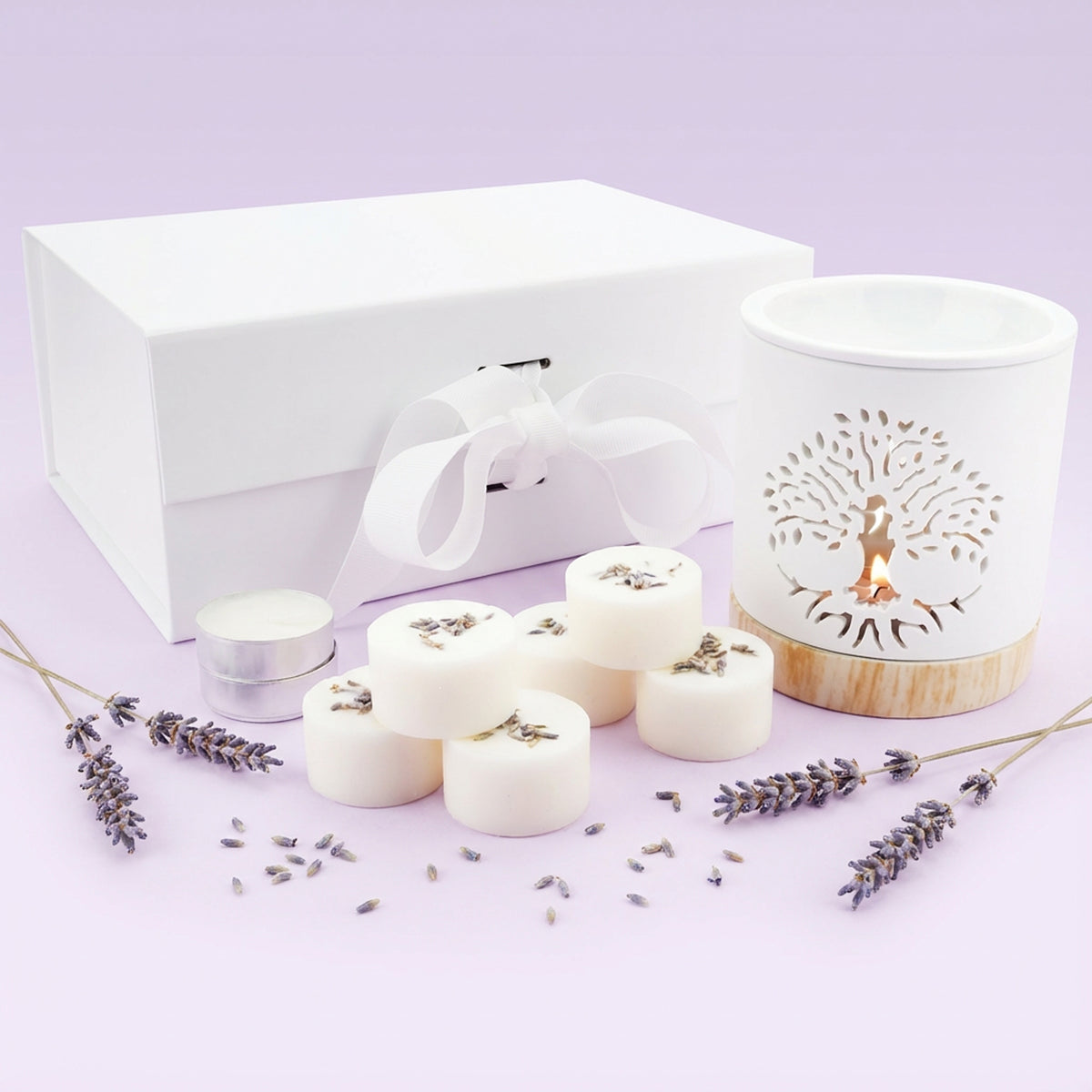 Set of white candles, a white box, and a decorative candle holder on a light purple background.