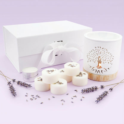 Set of white candles, a white box, and a decorative candle holder on a light purple background.